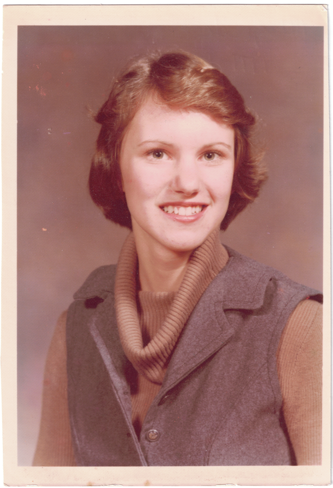 Kimberly Ann Miller posing for her 11th grade photo, wearing a sweater and vest she designed herself.