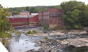 The old Collins Mill in Collinsville, Connecticut as viewed from the bridge on Connecticut Route 179. The Farmington River is visible in the foreground.