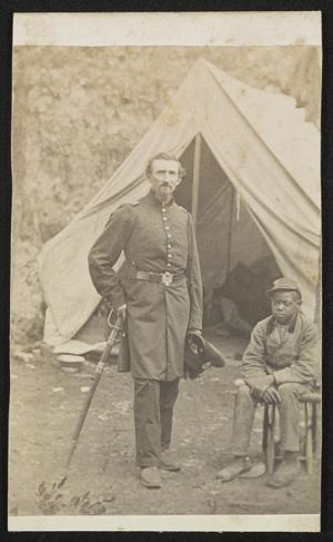 Major Luzerne Todd of Co. D, 23rd New York Infantry Regiment and Co. B, 86th New York Infantry Regiment in uniform with sword and unidentified young African American servant in front of tent