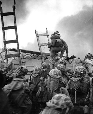 1st Lt Baldomero Lopez, USMC, leads the 3rd Platoon, Company A, 1st Battalion, 5th Marines over the seawall- N side of Red Beach