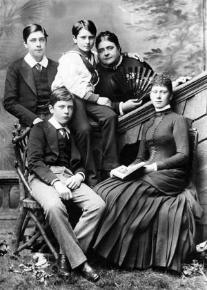 The Duchess of Teck and her family c. 1880; Prince Alexander sits centre with his arm around the Duchess, Princess Mary (later Queen Mary) is seated at far right